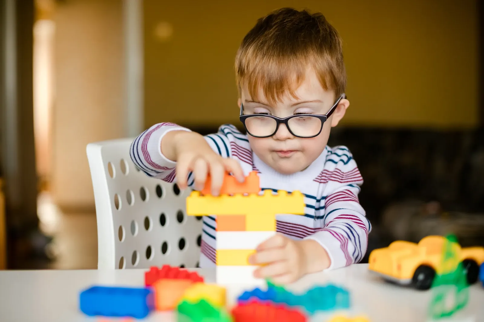Child with glasses building lego blocks