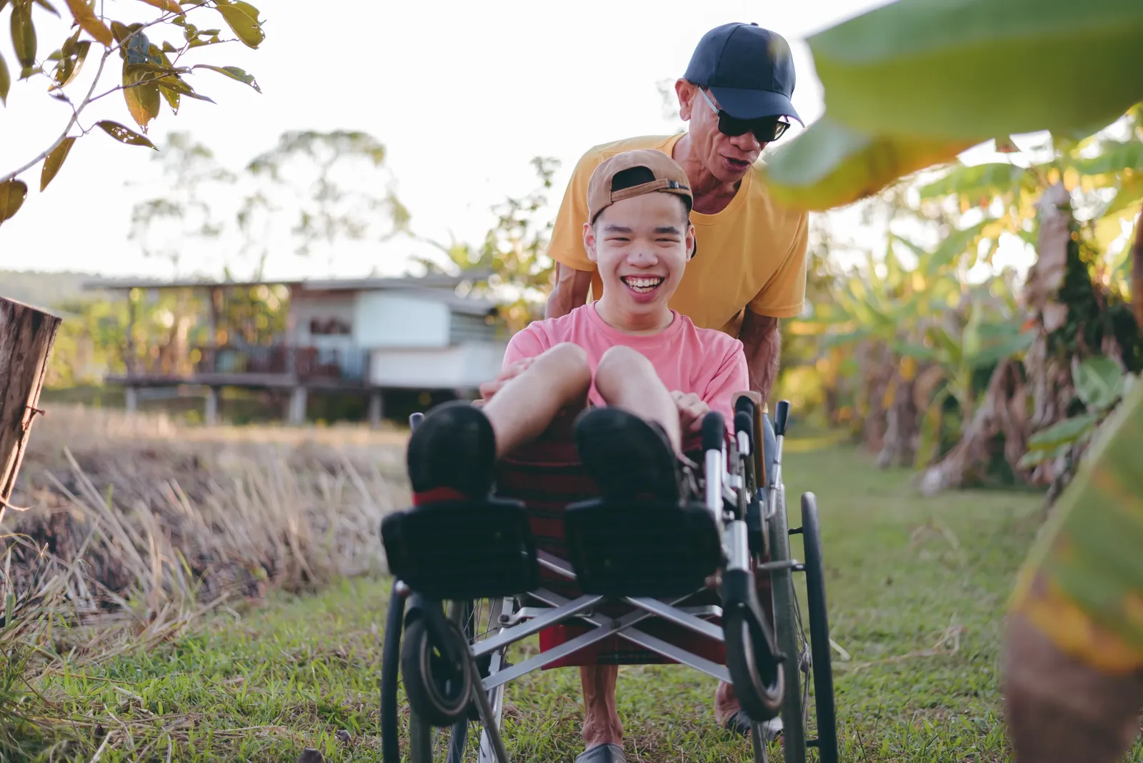Father pushing son in wheelchair outdoors
